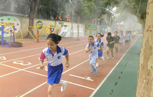 北林附小打开了校园内的喷雾设施，让学生们在凉爽舒适的环境中锻炼身体.jpg